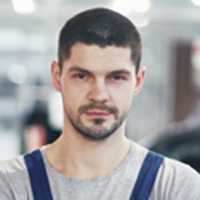 A man with short hair and beard wearing blue overalls.