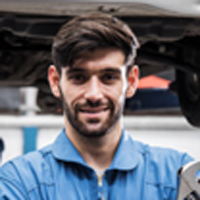 A man in blue shirt holding wrench near car.