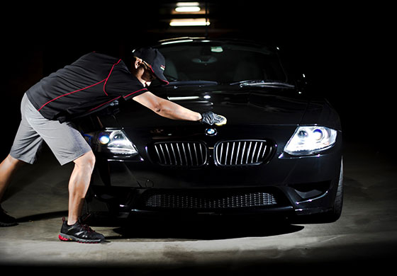 A man is cleaning the hood of his car.