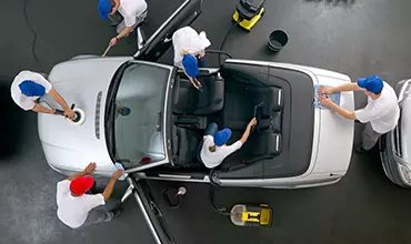 A group of men cleaning the hood of a car.